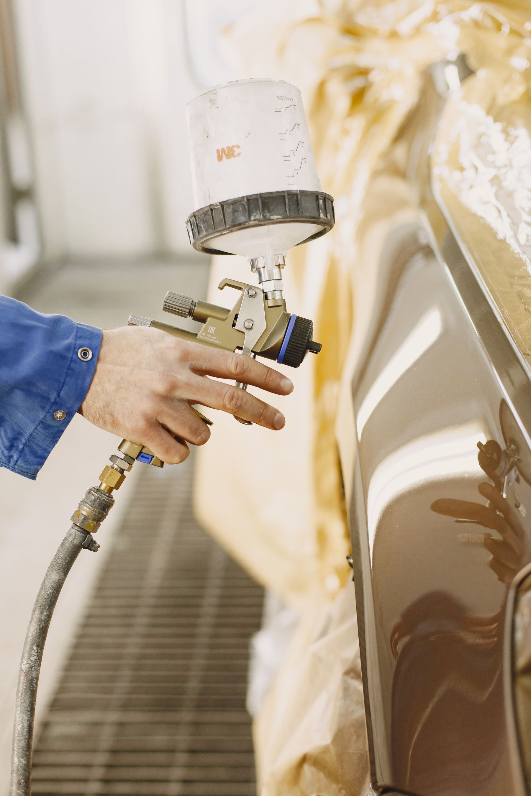 Technician spraying a car panel with an HVLP gun